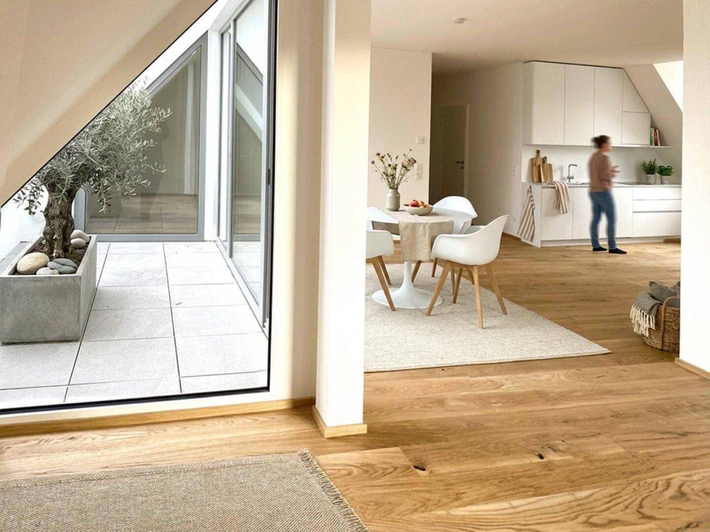 Moderner Wohnbereich mit Essplatz und offener Küche, direktem Zugang zur sonnigen Terrasse.