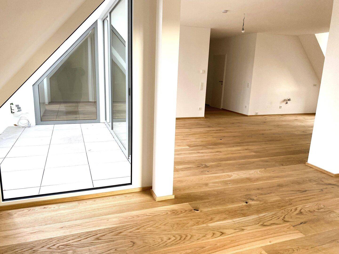 Geräumiger, heller Wohnbereich mit Holzboden und großen Glasfronten zur Terrasse.