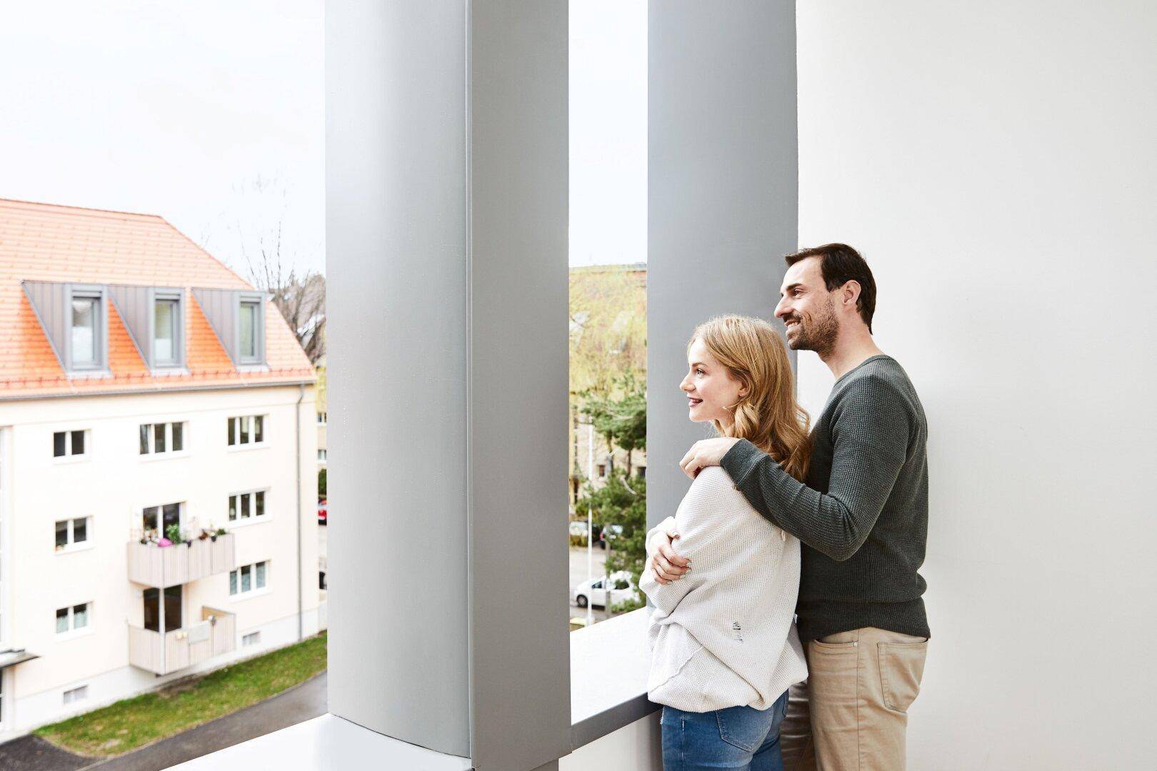Paar genießt den Ausblick vom Balkon auf die umliegende Wohngegend.