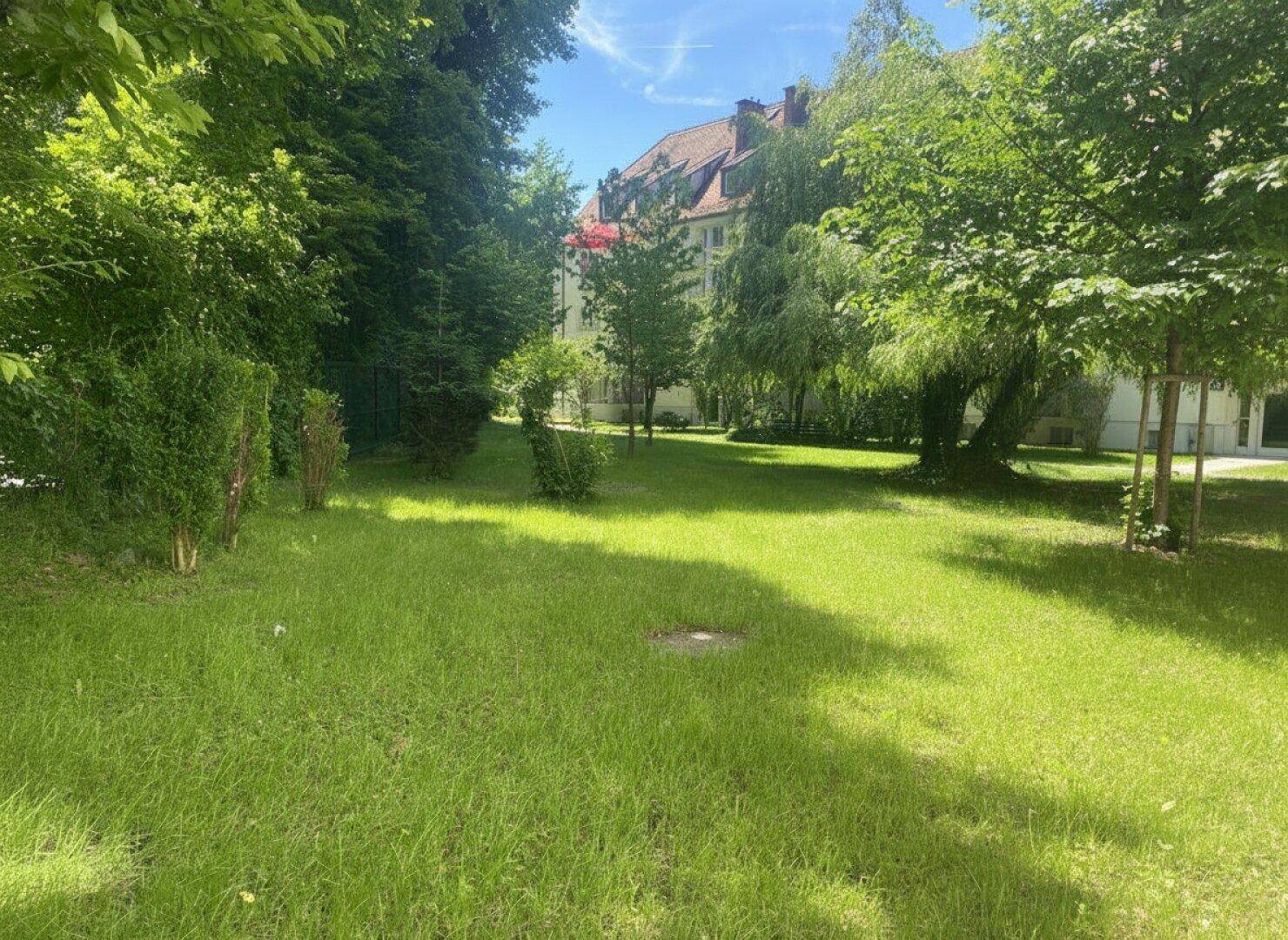 Weitläufige Grünfläche mit Rasen und Bäumen, die eine ruhige und natürliche Umgebung schafft.