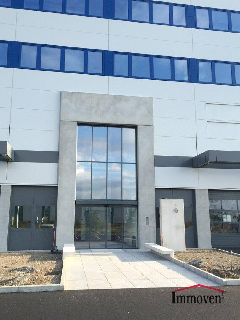 Hauptzugang des modernen Gewerbegebäudes mit breiter Rampe und hoher Glasfront.