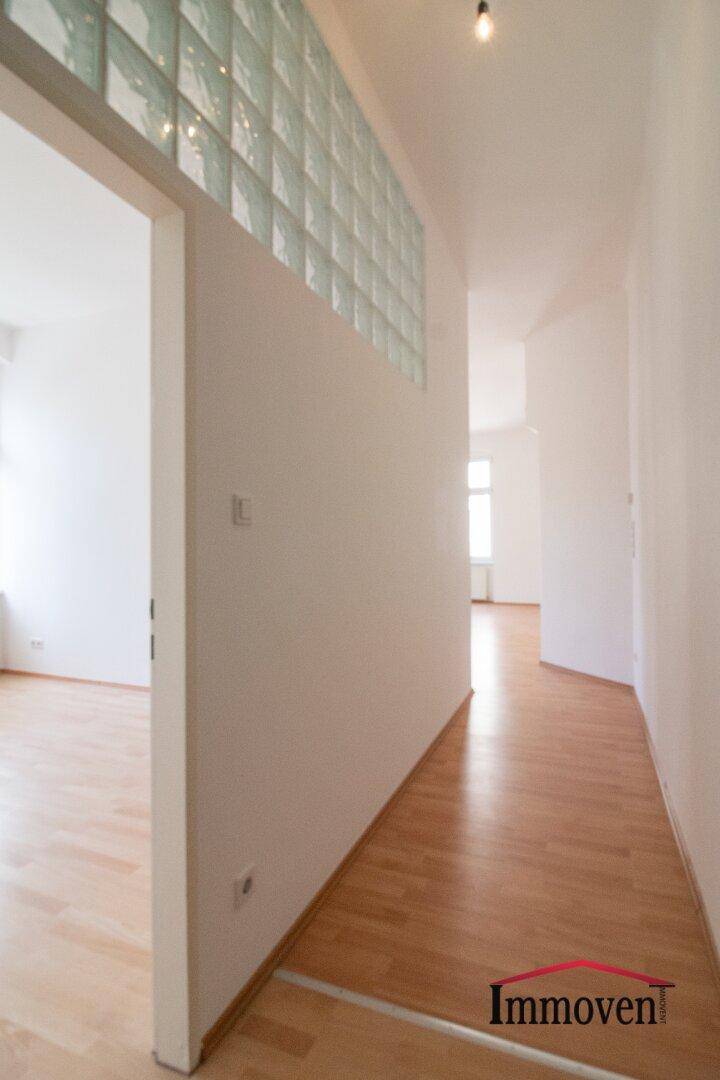 Heller Flur mit Parkettboden und einer Wand aus Glasbausteinen, die Licht in den Raum lässt.
