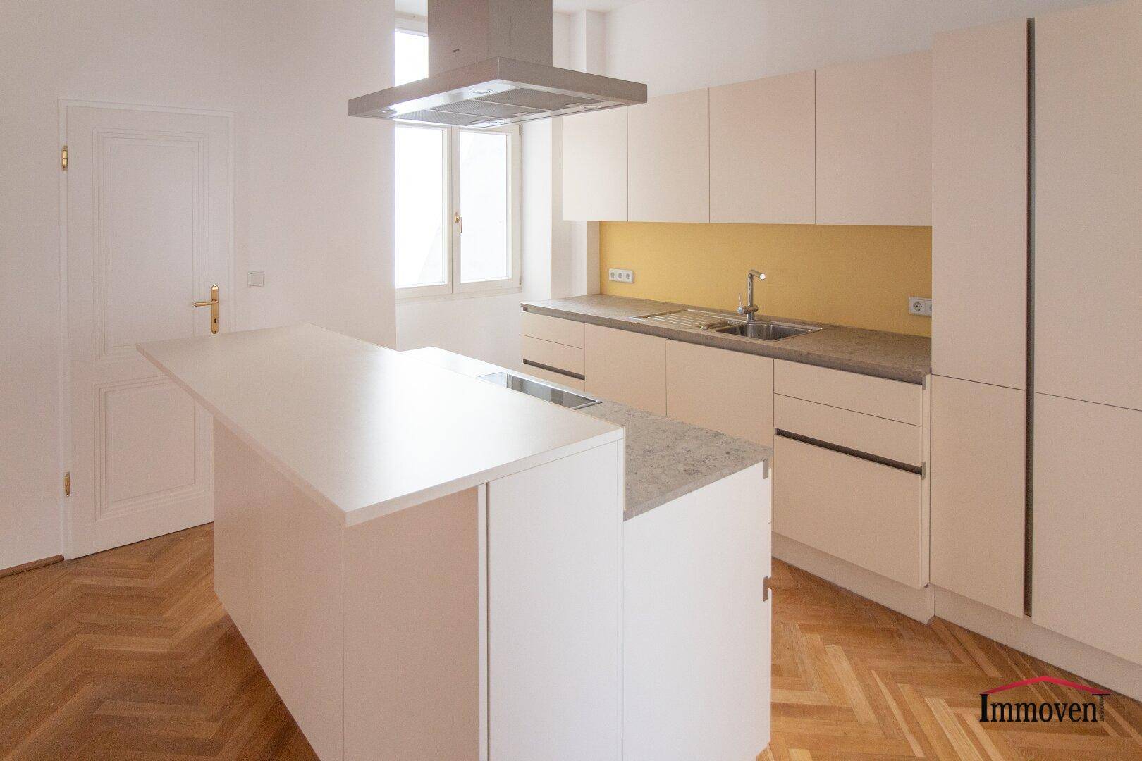 Nahaufnahme einer modernen Küche mit Kücheninsel, Induktionskochfeld und Dunstabzugshaube.