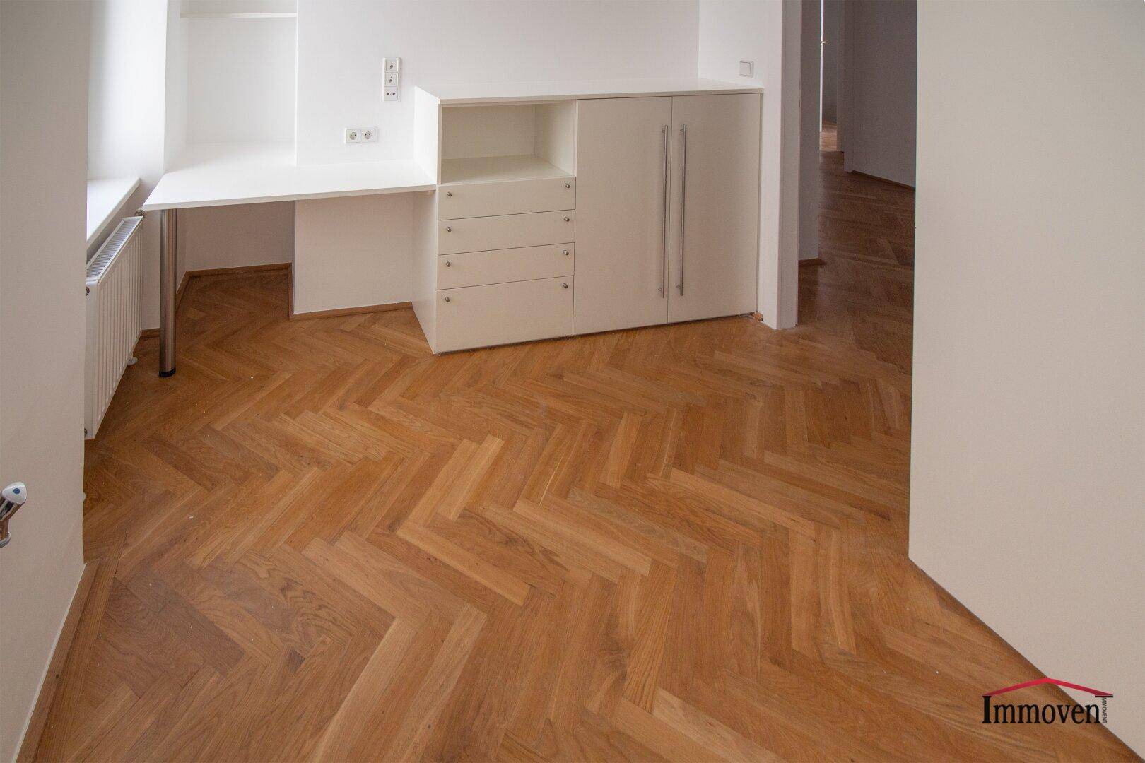 Arbeitsbereich mit Schreibtisch und Schränken, ideal für ein Home-Office, auf Fischgrätparkett.