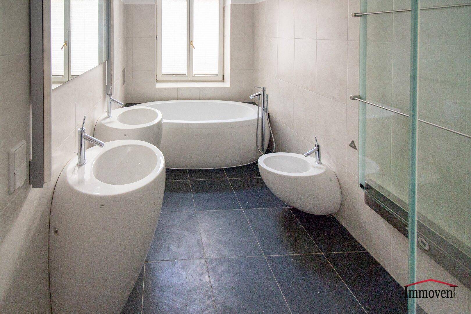 Modernes Badezimmer mit zwei Waschbecken, einer Badewanne und einer Duschkabine.