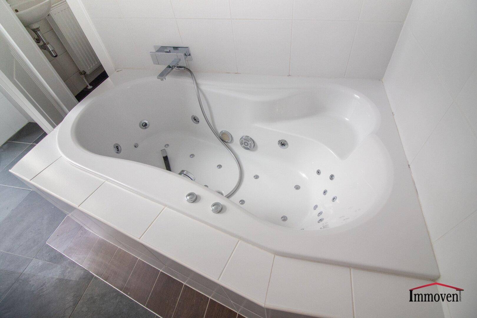 Whirlpool-Badewanne mit Fliesenrand in einem modernen Badezimmer, ideal zur Entspannung.