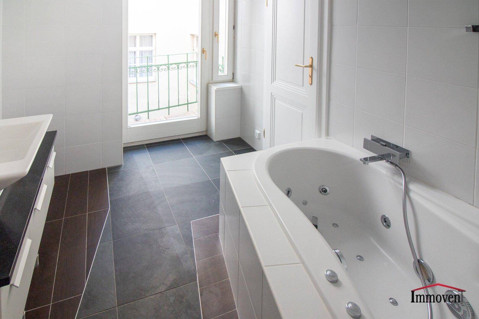 Badezimmer mit Whirlpool-Badewanne und Zugang zu einem kleinen Balkon.
