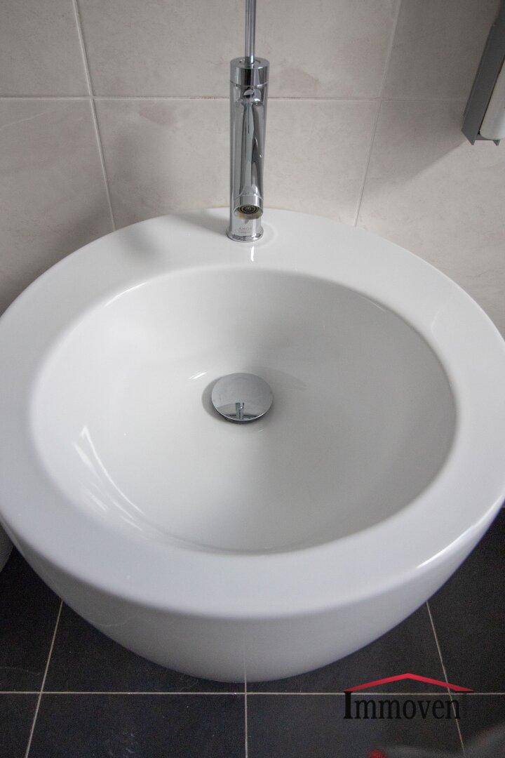 Modernes Waschbecken mit Chromarmatur in einem gefliesten Badezimmer.