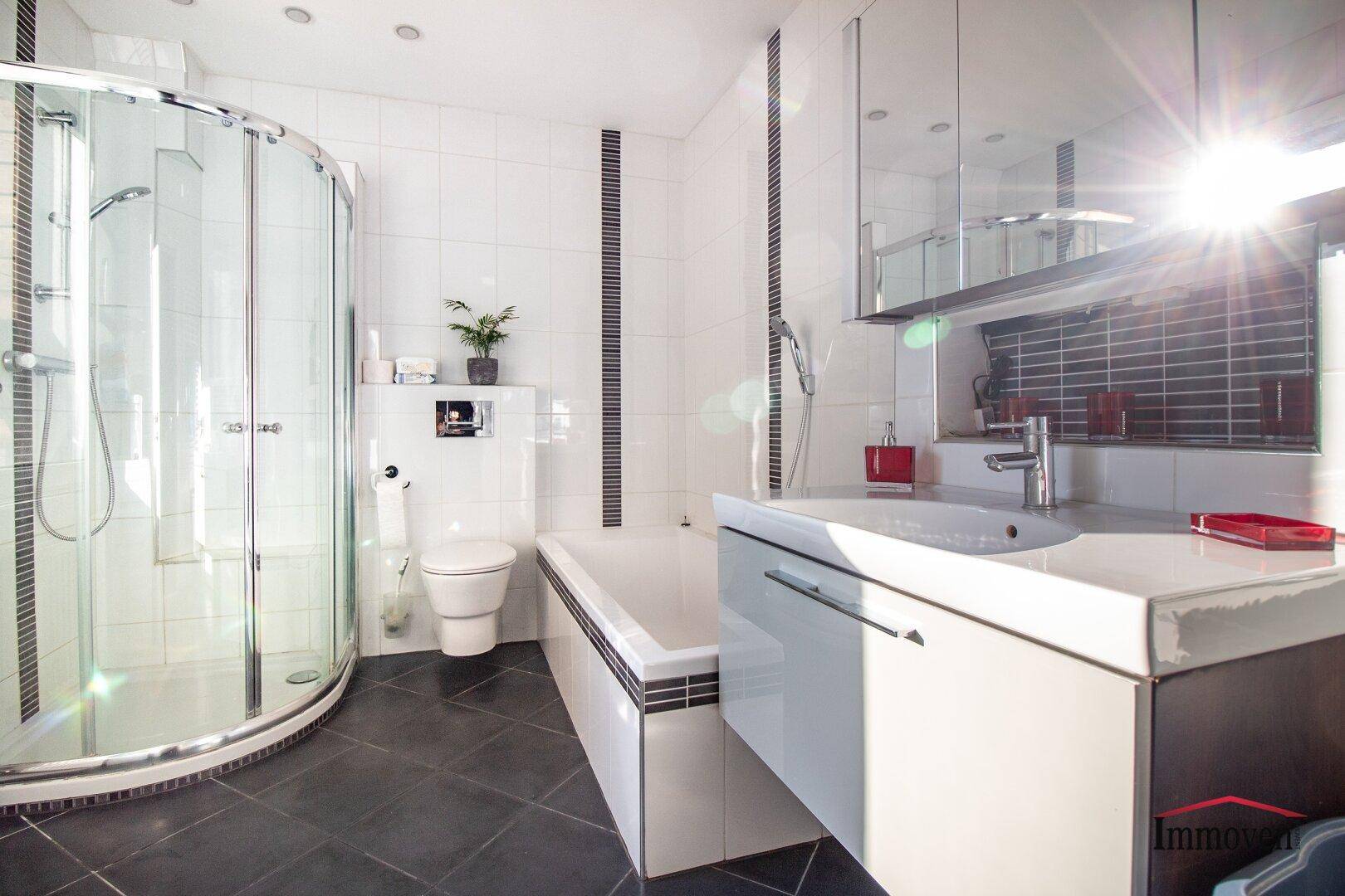 Modernes Badezimmer mit Dusche, Badewanne, Waschtisch und viel natürlichem Licht.