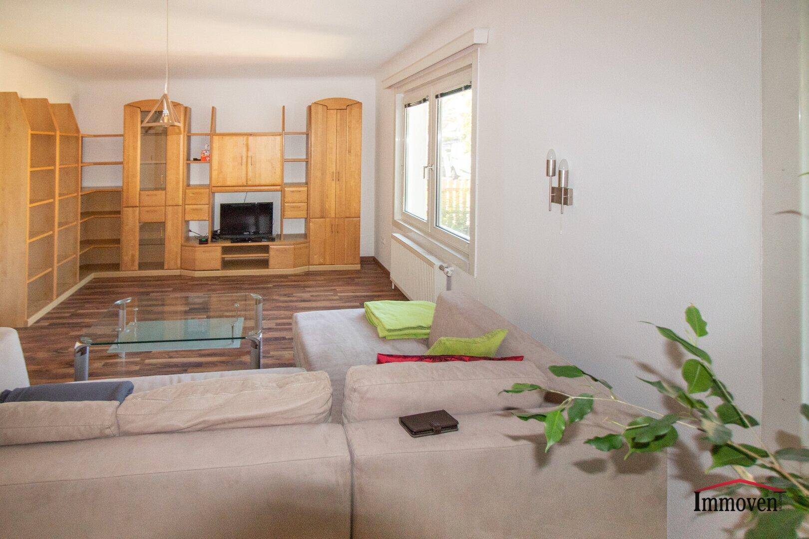 Geräumiges Wohnzimmer mit Holzboden, Sofa und einer großen Schrankwand.