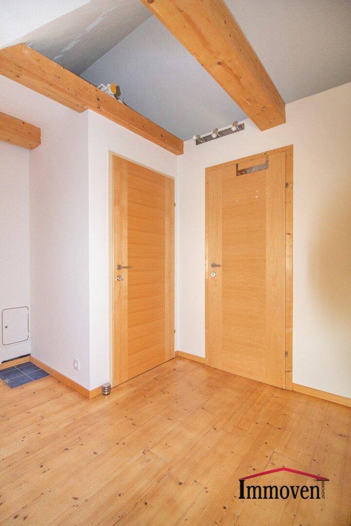 Innenraum mit Holzbalken an der Decke und zwei Holztüren.