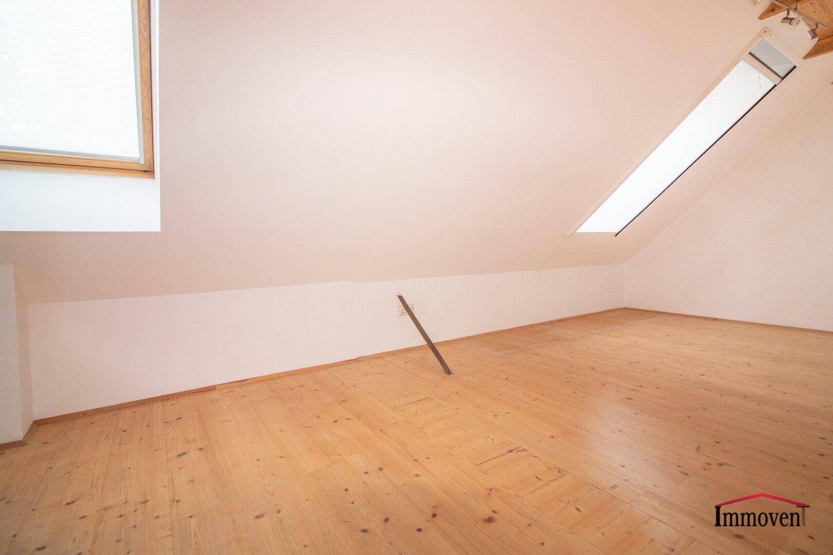 Leerer Raum im Dachgeschoss mit Holzboden und Dachfenstern, ideal für Ausbau.