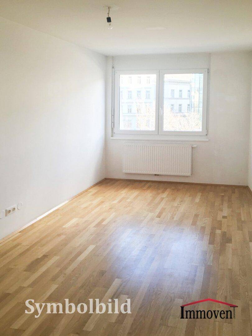Leerer, heller Raum mit Holzboden und einem Fenster, das viel Tageslicht hereinlässt.