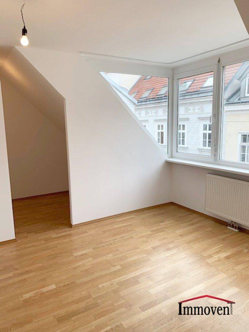 Geräumiges Dachgeschosszimmer mit Parkettboden, schrägen Wänden und viel Tageslicht durch große Fenster.
