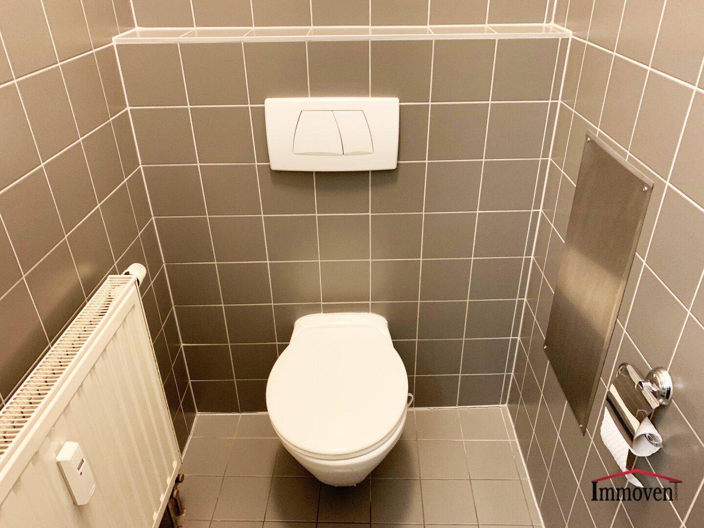 Sauberer Toilettenbereich mit grauen Fliesen und wandhängendem WC, funktional und gepflegt.