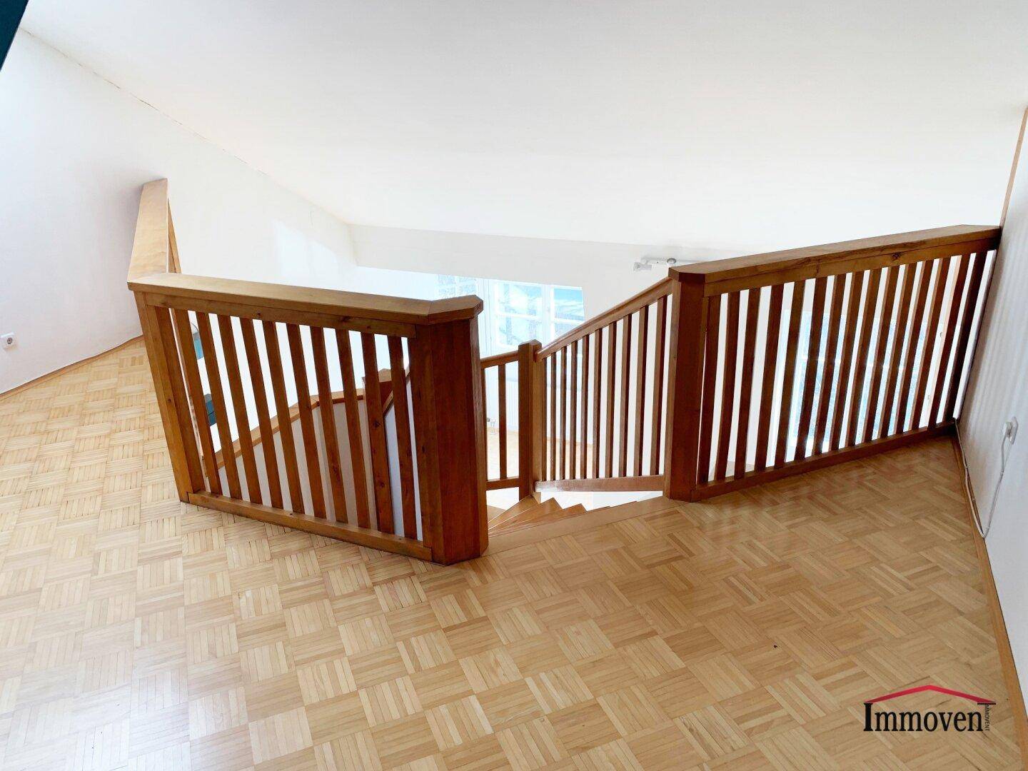 Blick von oben auf die Holztreppe und den Treppenabsatz mit Parkettboden.