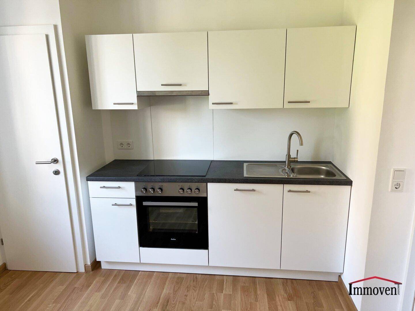 Detailansicht der modernen weißen Einbauküche mit Kochfeld, Backofen und praktischer Arbeitsfläche.