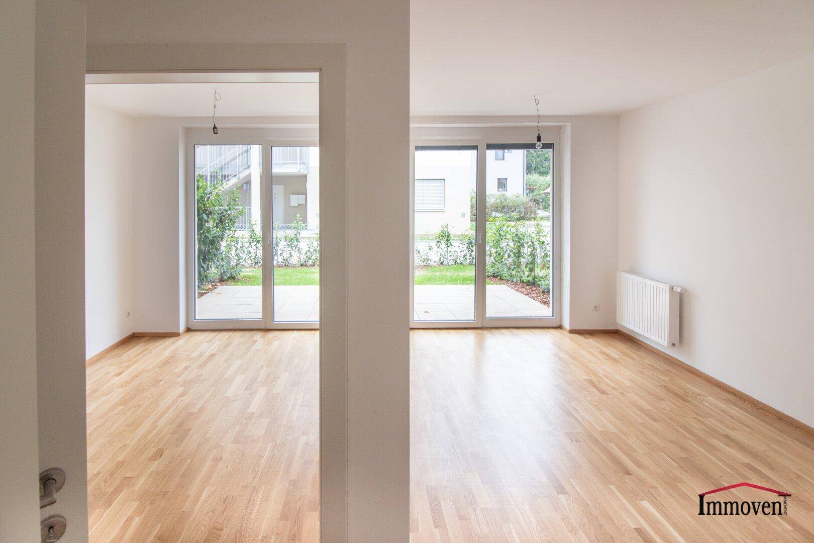 Geräumiger, heller Innenraum mit Holzboden und großen Fenstern zum Garten.