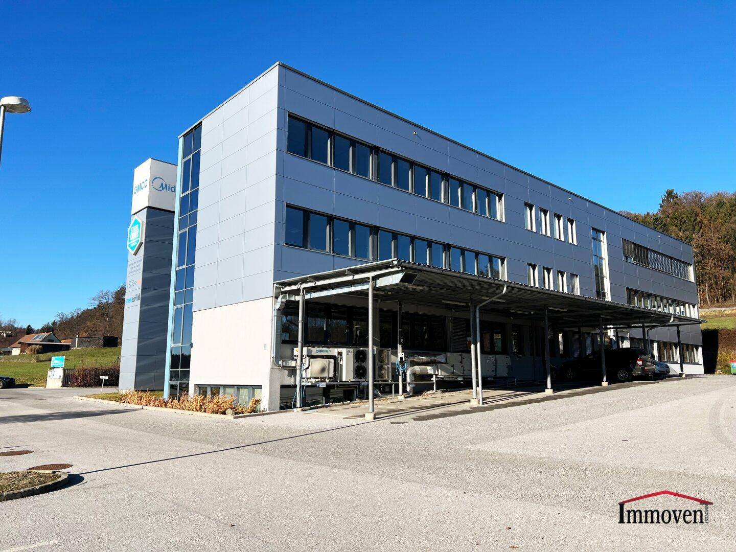 Ansicht des modernen Bürogebäudes von der Seite mit überdachtem Bereich und Parkplätzen.
