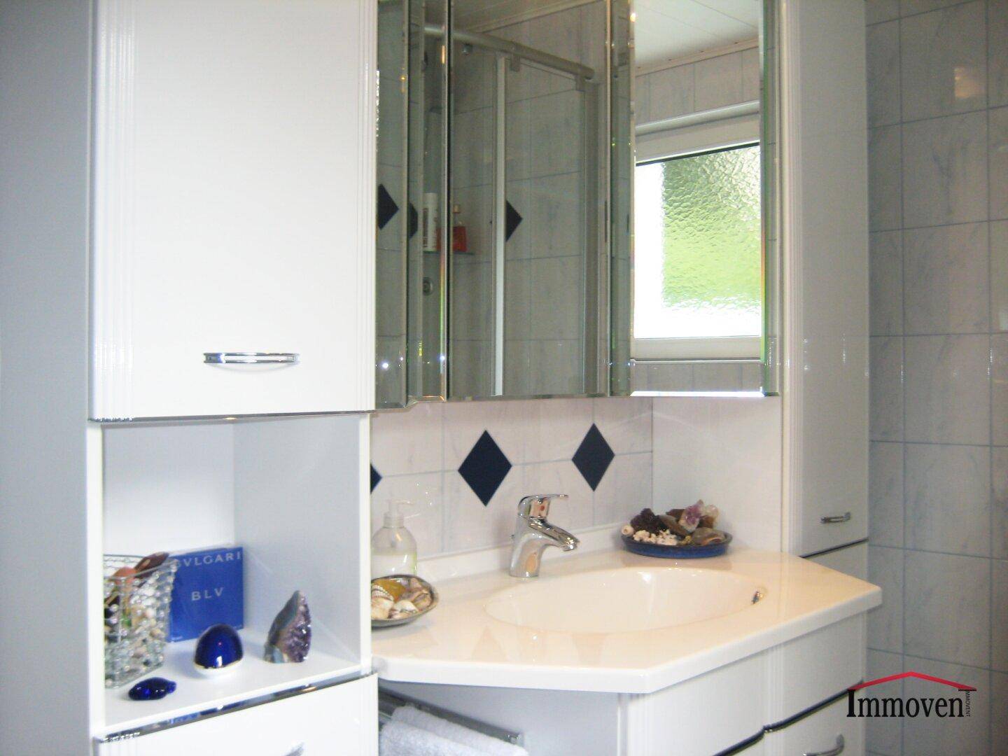 Badezimmer mit modernem Waschtisch, Spiegelschrank und hellen Fliesen.