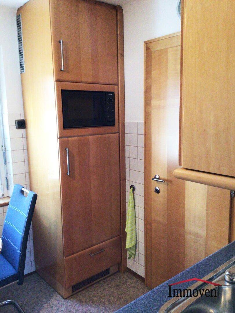 Küchenzeile mit integrierter Mikrowelle und hohen Holzschränken, praktisch gestaltet.
