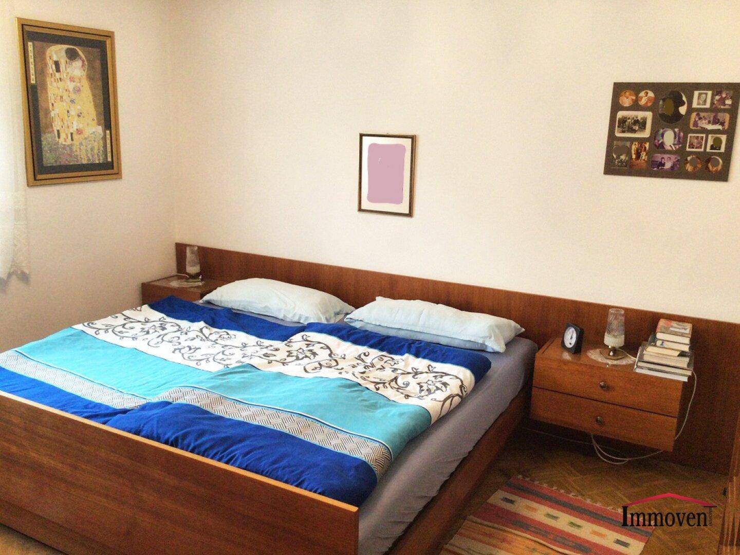 Schlafzimmer mit Doppelbett, Holzbettrahmen und Nachttischen, hell und funktional.
