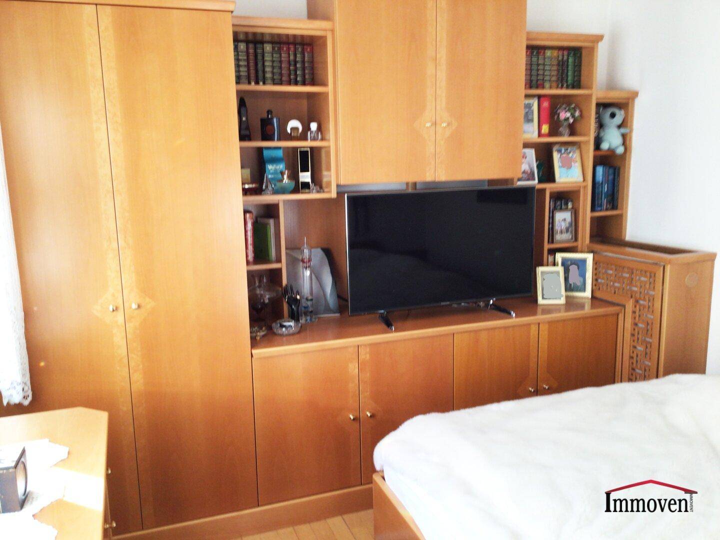 Schlafzimmer mit integrierten Holzschränken, Bücherregalen und einem Fernsehbereich.