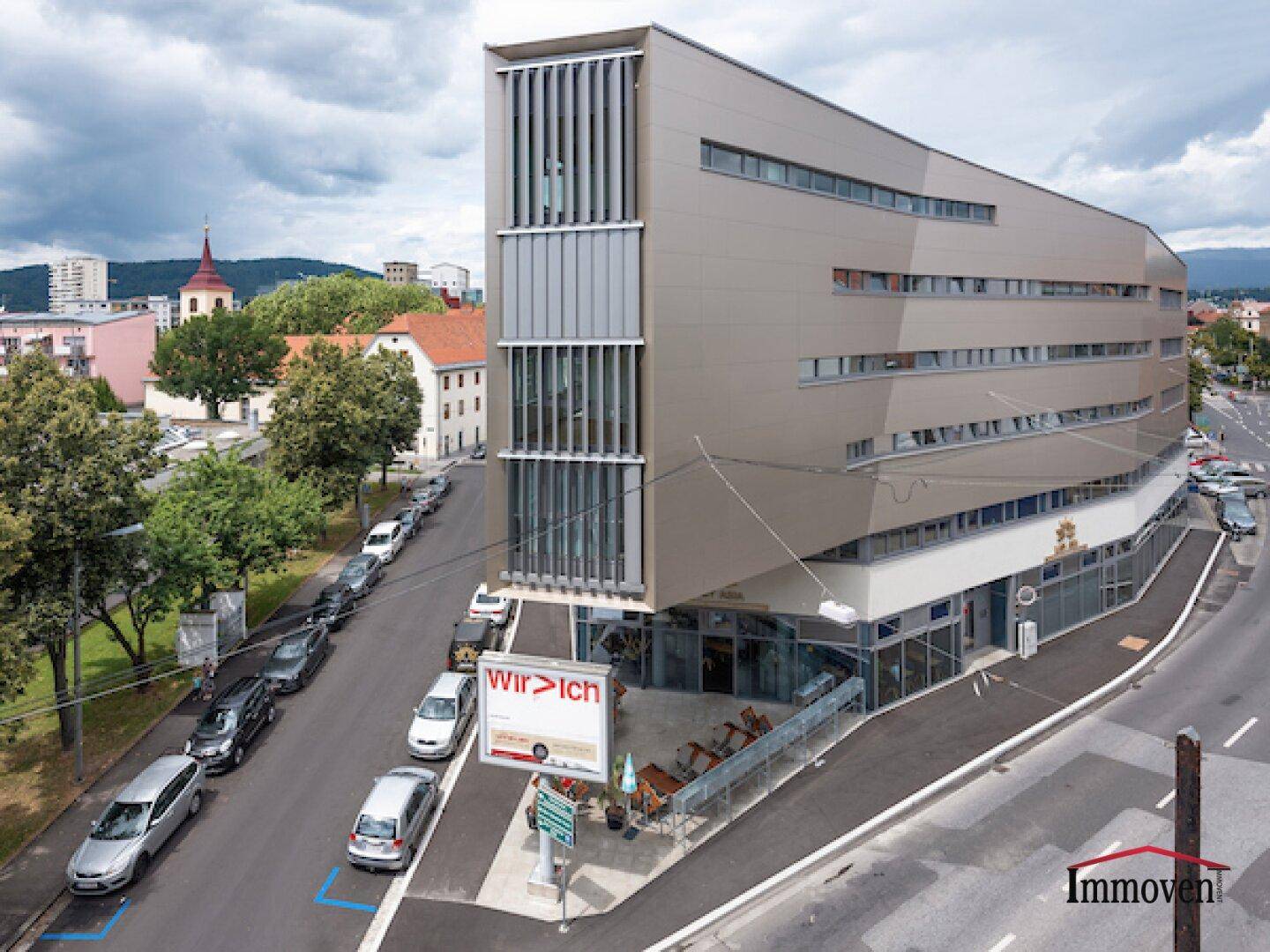 Modernes Bürogebäude mit markanter Fassade und großen Fensterfronten an einer belebten Straße.