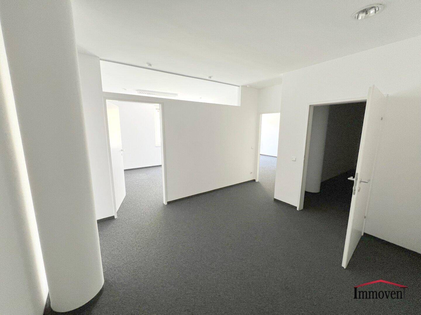 Großes Büro mit Teppichboden und mehreren Zugängen zu weiteren Räumen, ideal für flexible Arbeitsbereiche.