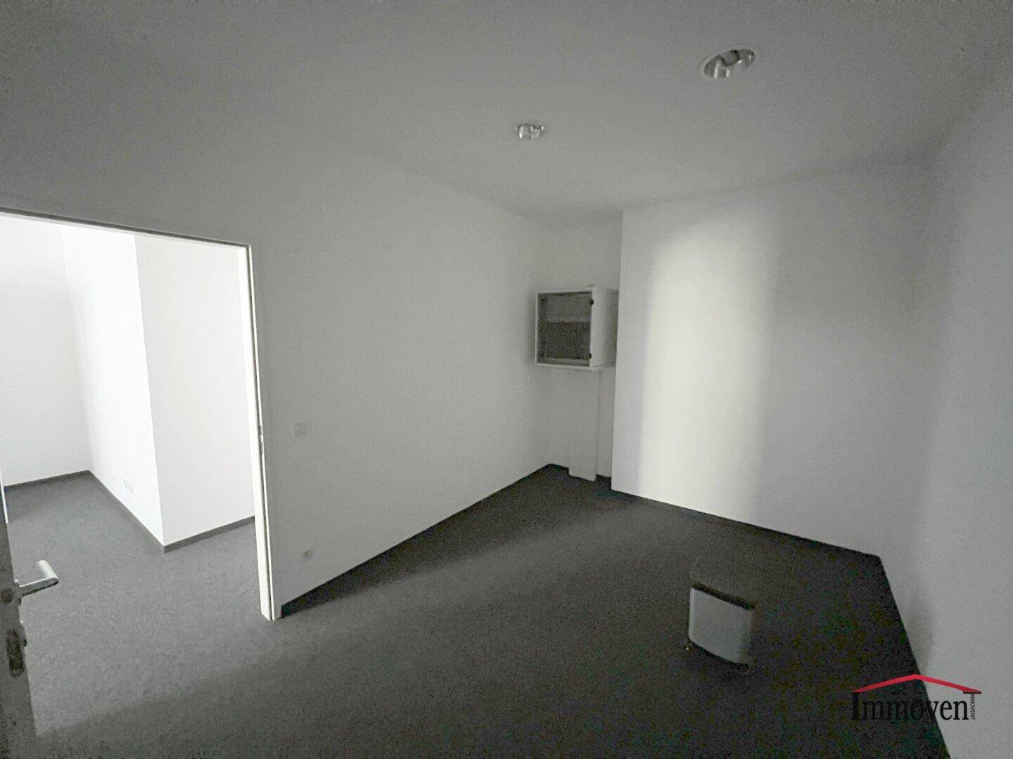 Büro mit Teppichboden und einem Fenster, das eine angenehme Arbeitsatmosphäre schafft und gut belichtet ist.