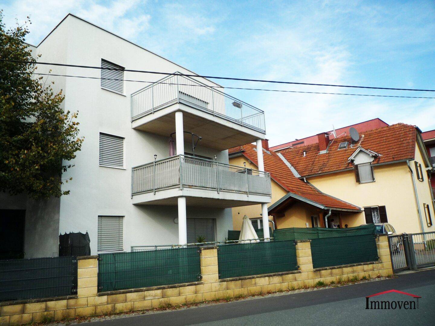 Seitenansicht des modernen Apartmentgebäudes mit gestuften Balkonen und dem angrenzenden Haus.