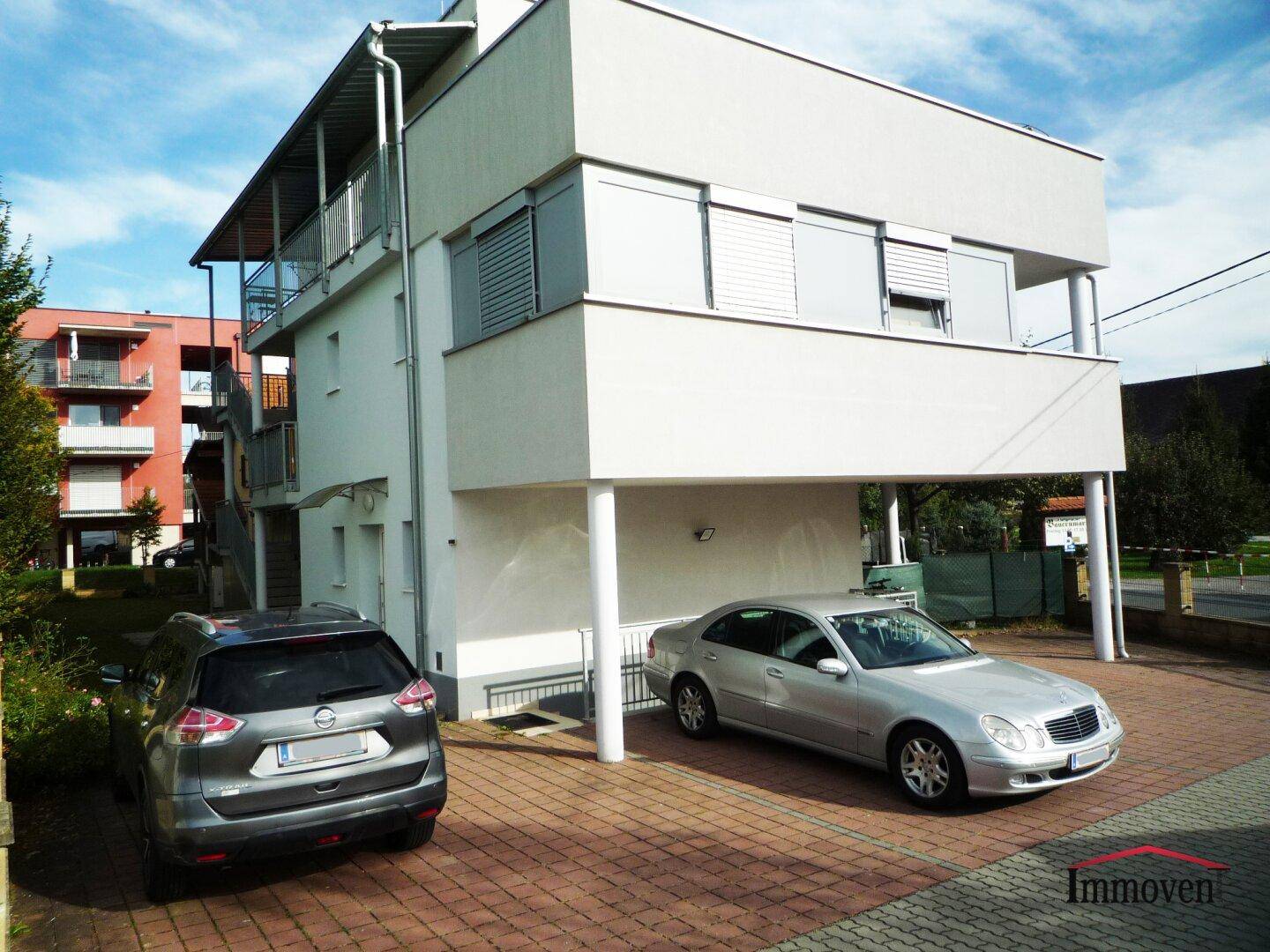 Moderne Architektur des Apartmentgebäudes mit überdachten Parkplätzen und Balkonen.