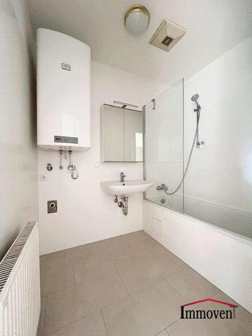 Modernes Badezimmer mit Badewanne, Dusche, Waschbecken und Heizkörper.