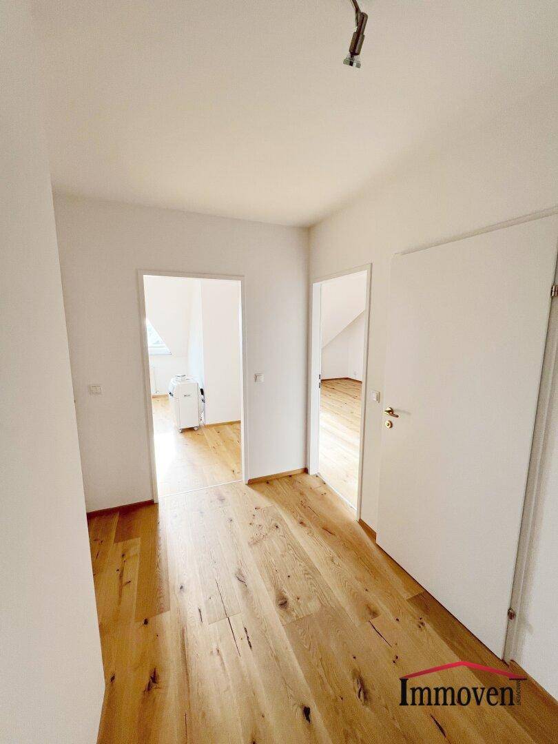 Heller Flur mit Holzboden und weißen Türen, der zu verschiedenen Zimmern führt.