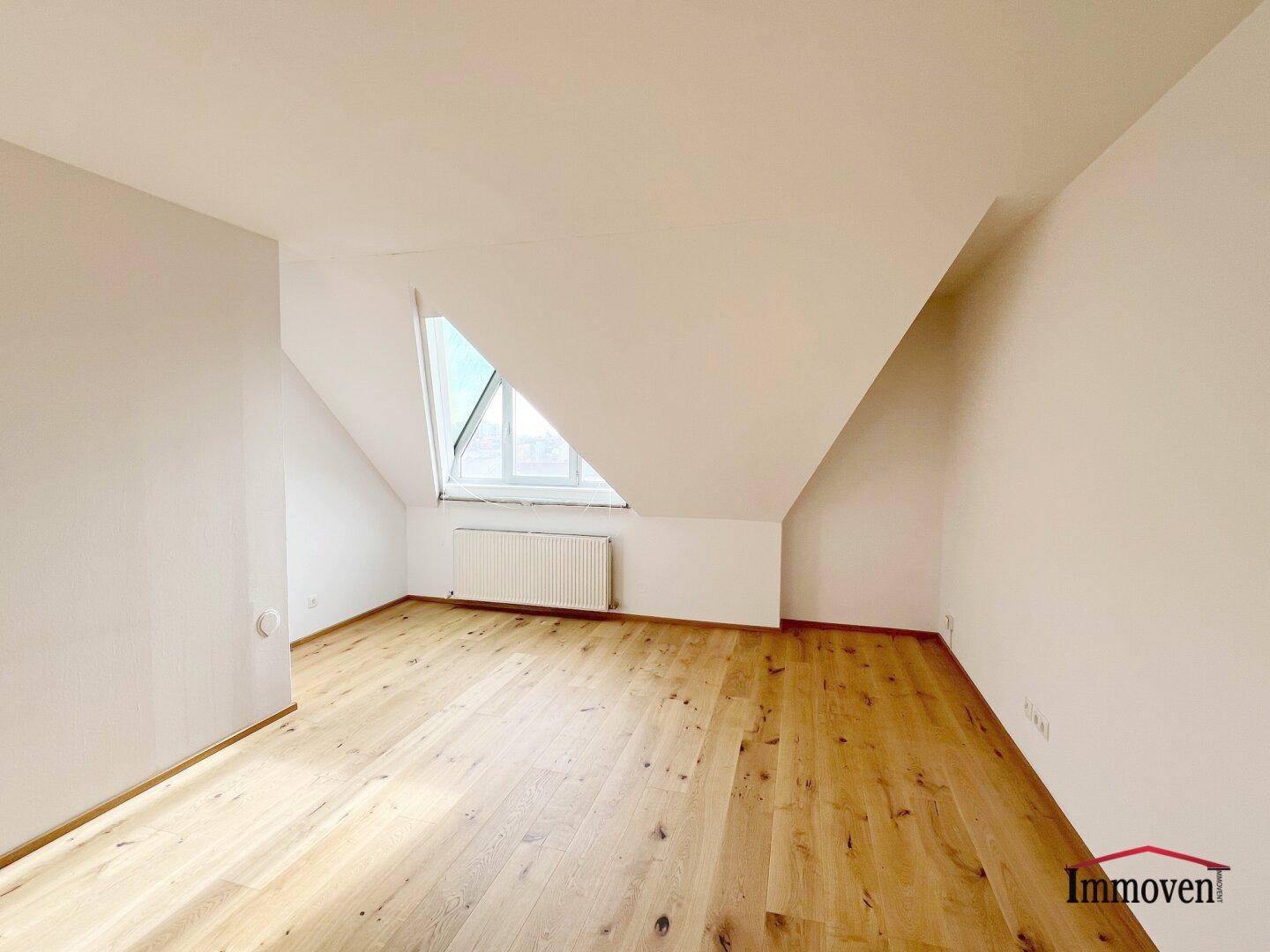 Geräumiges Dachzimmer mit hellem Holzboden und schrägen Wänden, ideal für individuelle Gestaltung.