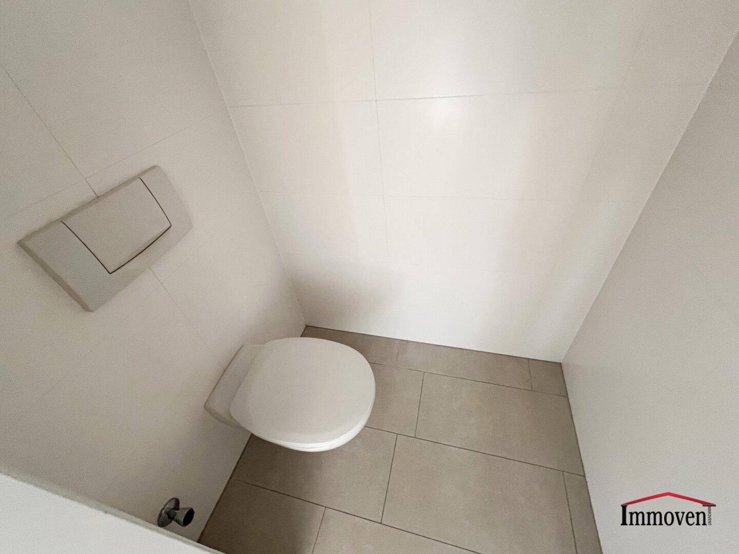 Separates WC mit wandhängender Toilette und modernen Fliesen.