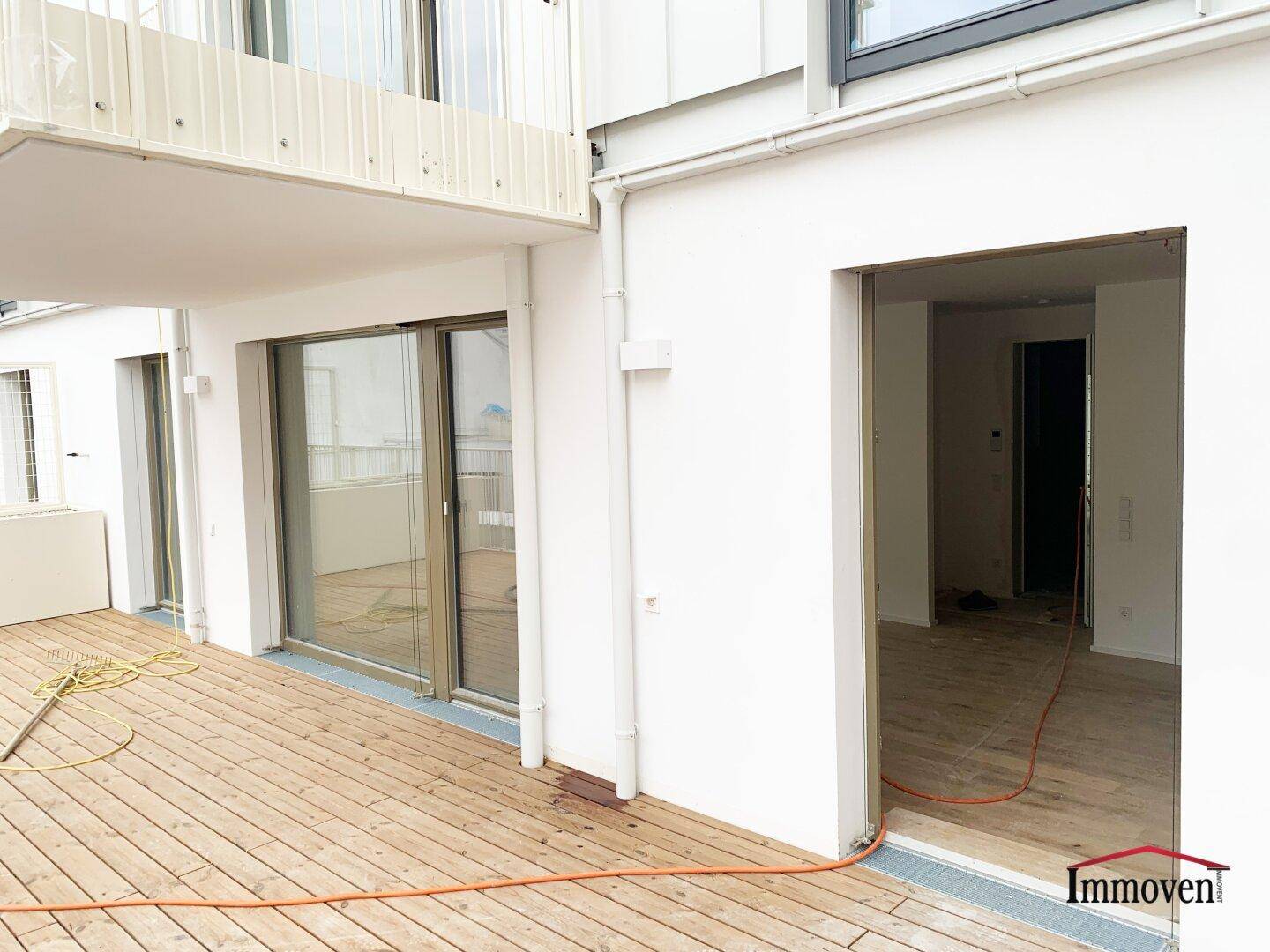 Breite Holzterrasse mit Schiebetüren zu den Wohnbereichen und viel Platz im Freien.