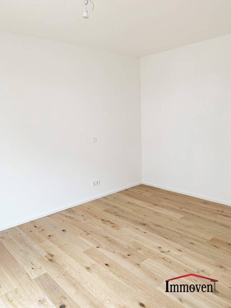 Leeres Zimmer mit hellem Holzboden und weißen Wänden, bereit zur individuellen Gestaltung.