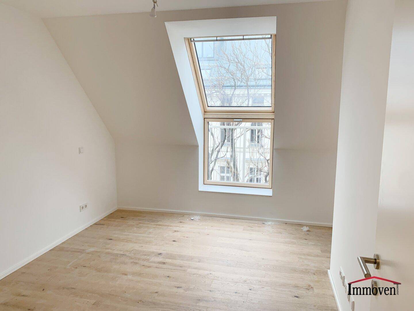Helles Schlafzimmer im Dachgeschoss mit schrägen Wänden und großem Dachfenster.