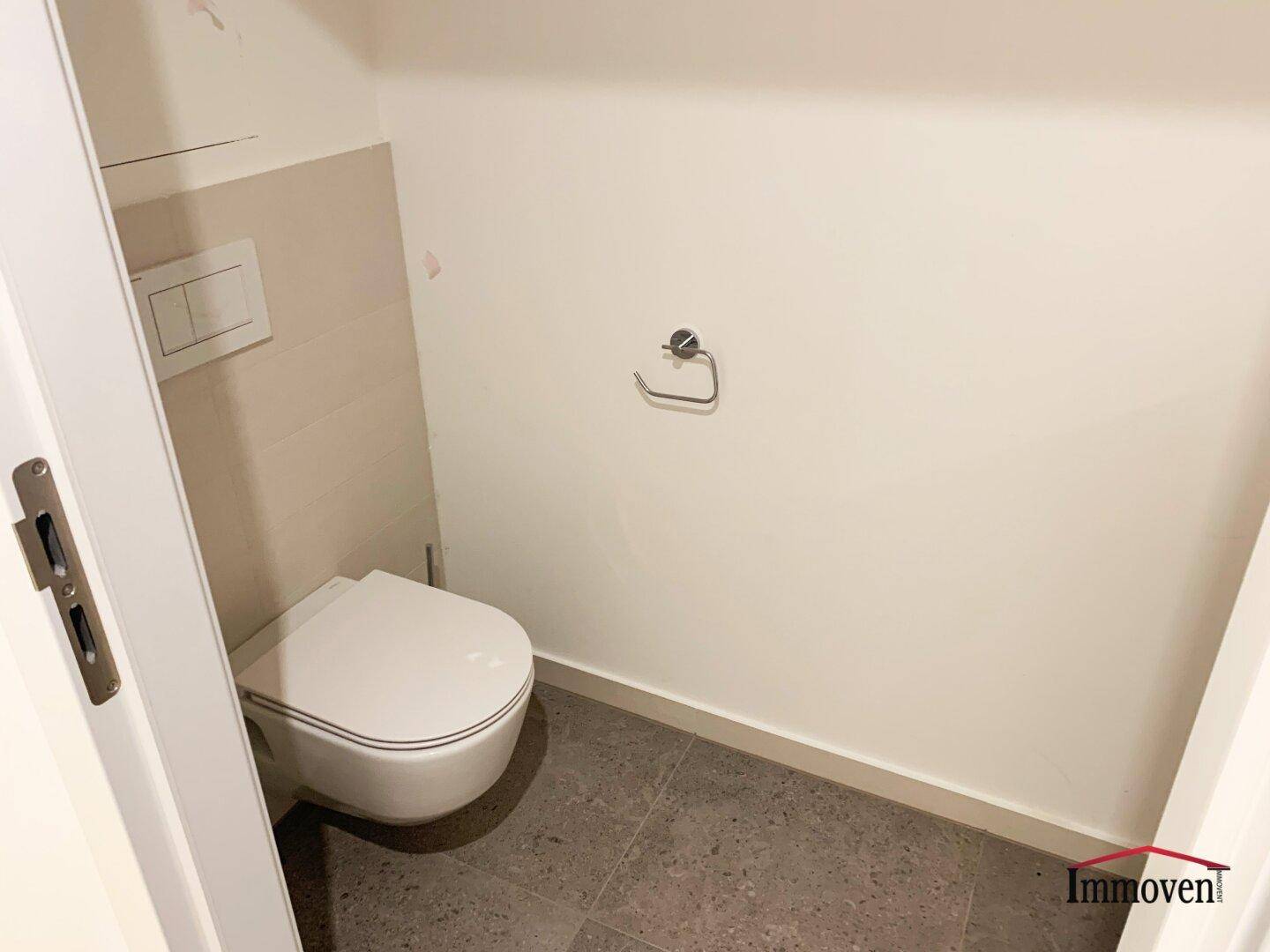 Separate Gästetoilette mit Wand-WC und dunklem Fliesenboden.
