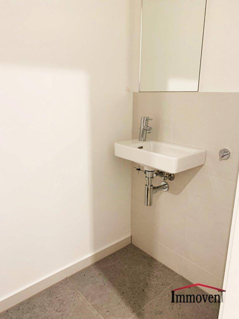 Kleine Gästetoilette mit Waschbecken und Spiegel in hellem Design.