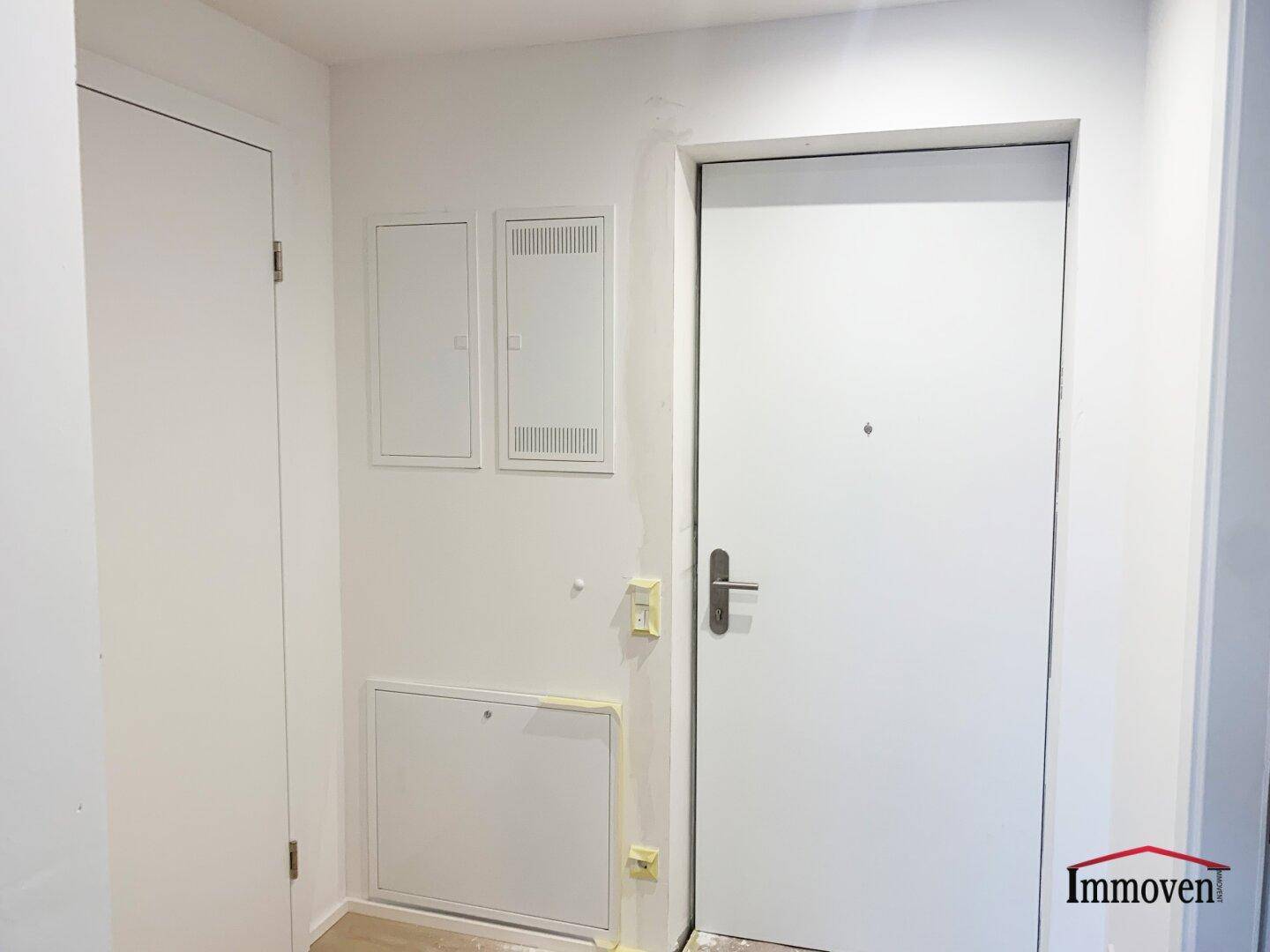Eingangsbereich einer Wohnung mit weißer Tür und Sicherungskästen.