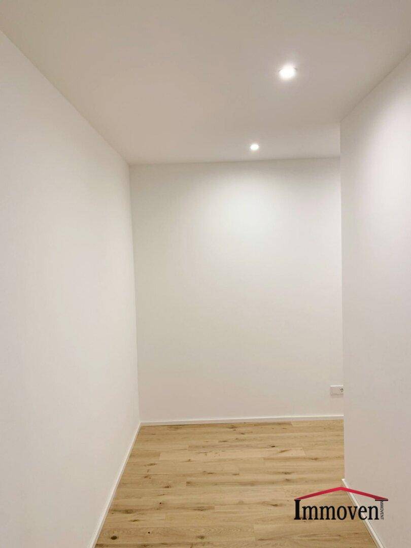Leerer, heller Flurbereich mit Holzboden und schlichten weißen Wänden.