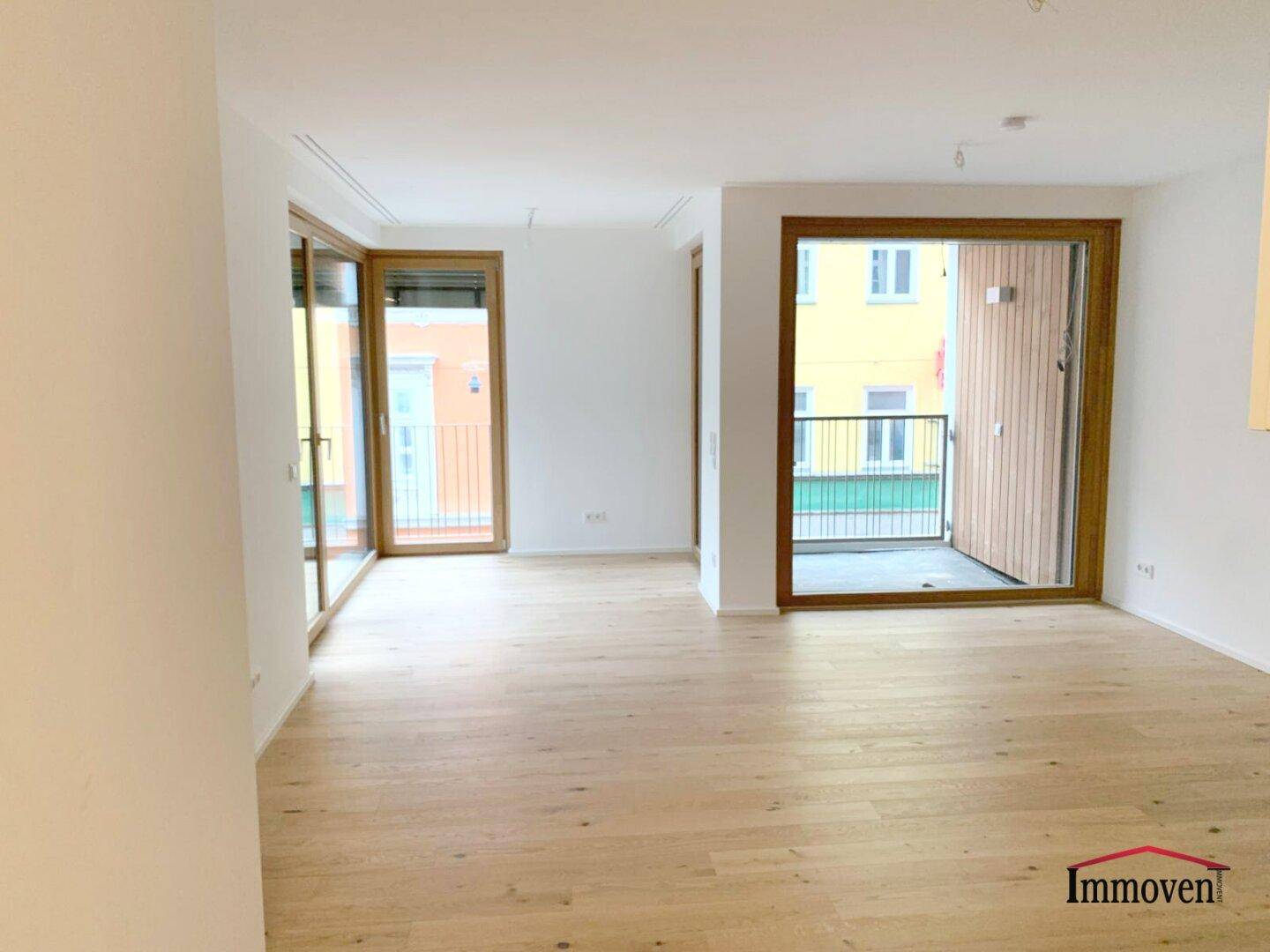 Geräumiger, heller Wohnbereich mit Holzboden und Zugang zu zwei Balkonen.