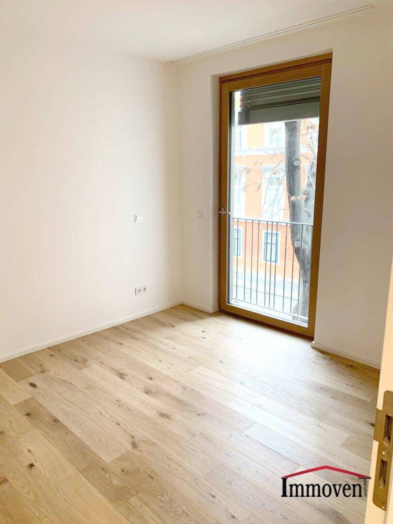 Helles Schlafzimmer mit Holzboden und Zugang zu einem französischen Balkon.