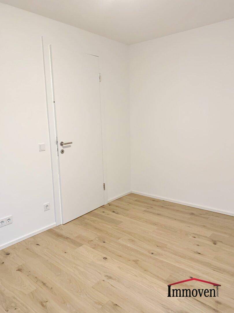 Leeres Zimmer mit Holzboden und weiß gestrichenen Wänden, bereit zur individuellen Gestaltung.
