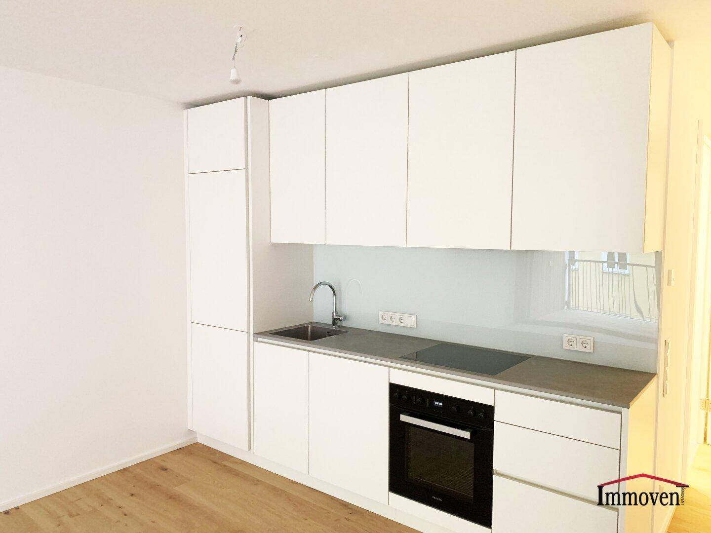 Detailansicht der modernen weißen Einbauküche mit Spüle, Kochfeld und Backofen.