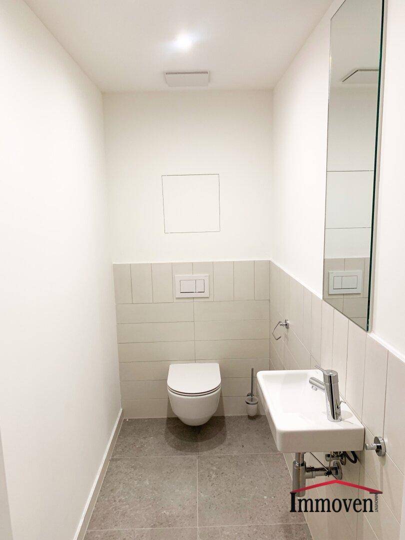 Separates Gäste-WC mit wandhängender Toilette und kleinem Waschbecken.