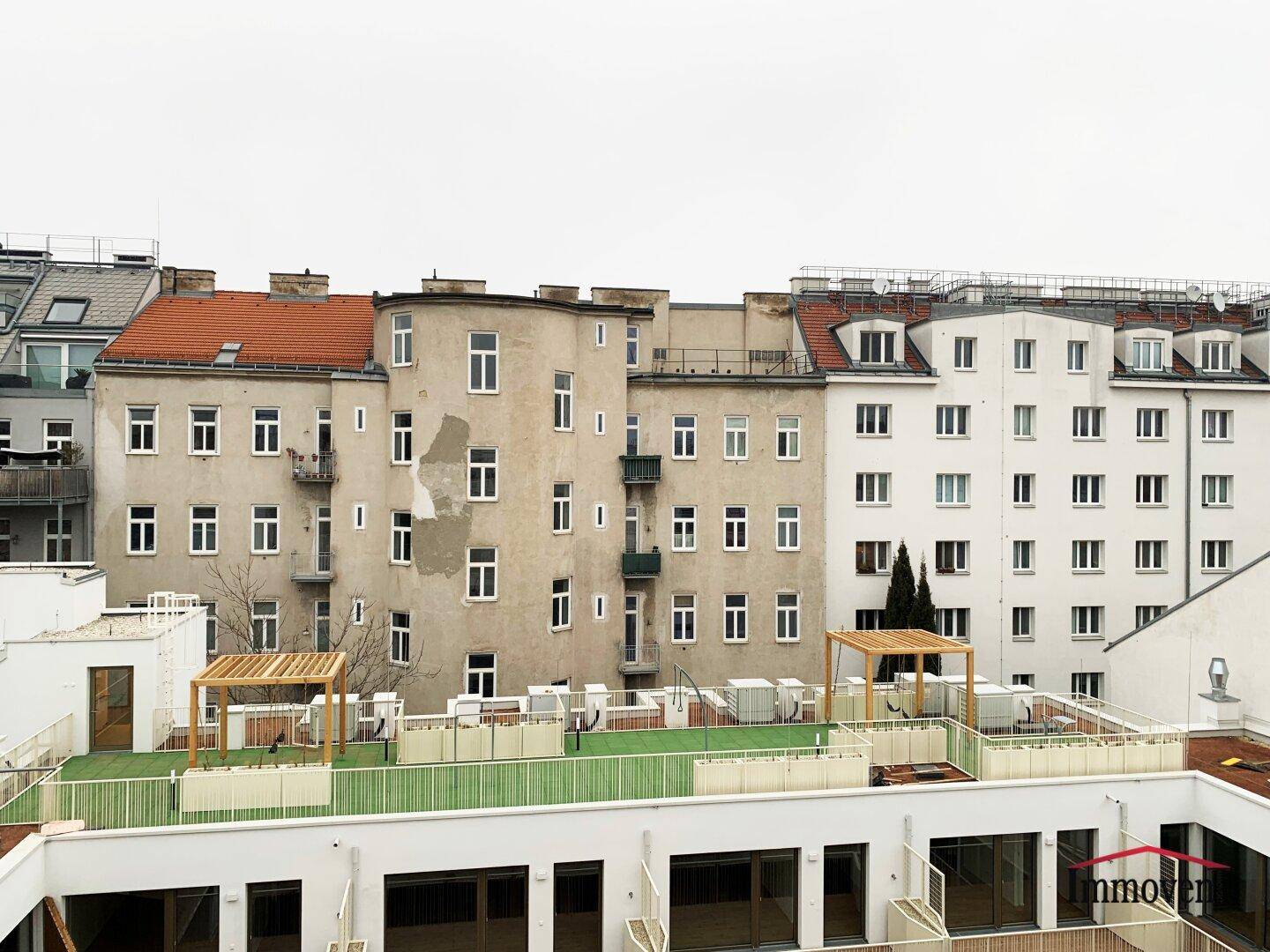 Dachterrassenbereich eines Neubaus mit Blick auf umliegende Gebäude und grüne Gestaltungselemente.
