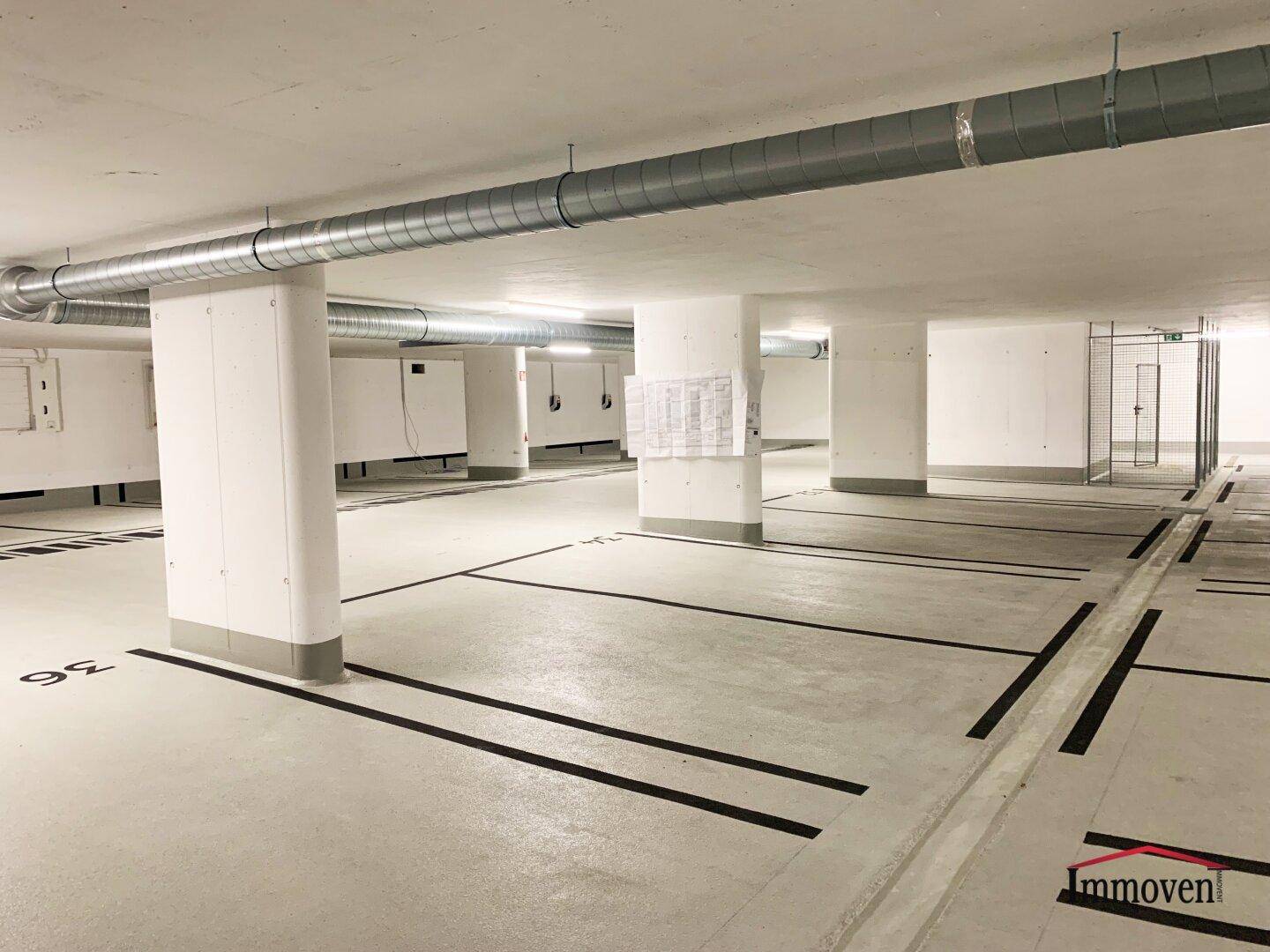 Tiefgarage mit markierten Stellplätzen und sichtbaren Lüftungsrohren.